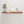 a wooden shelf with various decorative items on it, including a plant, a framed picture, and some white vases.