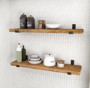 a set of two wooden shelves mounted on a white tiled wall, displaying various kitchen items such as bowls, bottles, and a teapot.