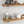 a wooden shelf with various kitchen items, including a bottle, a bowl, a teapot, and a salt and pepper shaker.
