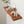a wooden shelf with various decorative items on it, including a plant, books, and two white vases.