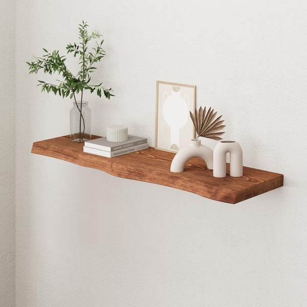 a wooden shelf mounted on a white wall, displaying various decorative items such as a plant, books, and a framed picture.