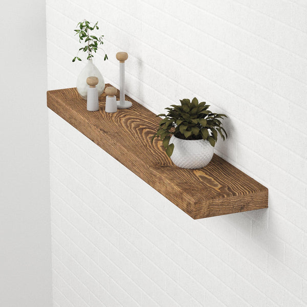 a wooden shelf mounted on a white wall, displaying various decorative items such as a potted plant, a vase, and a small sculpture.