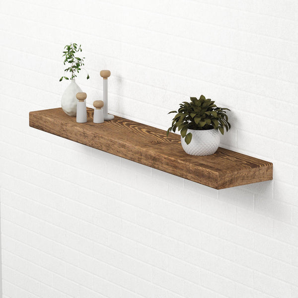 a wooden shelf mounted on a white wall, displaying various decorative items such as a potted plant, a vase, and a small sculpture.
