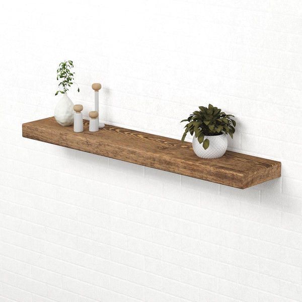 a wooden shelf mounted on a white brick wall, displaying a variety of decorative items, including a potted plant, a vase, and three small figurines.