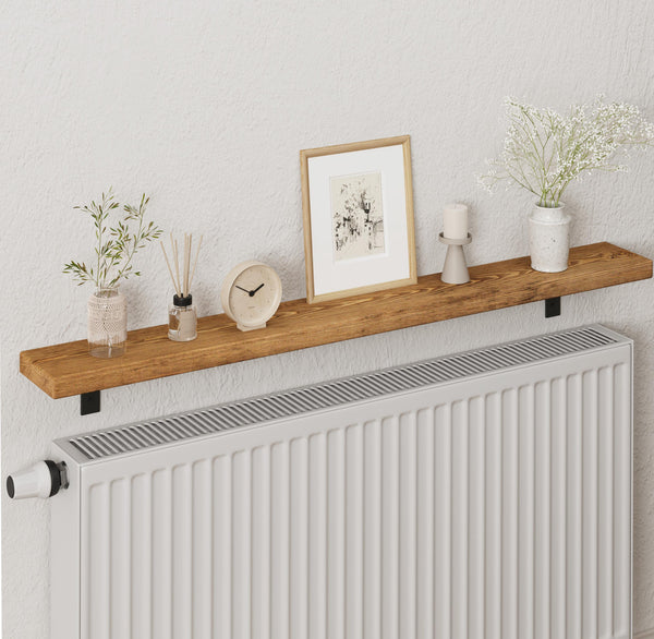 a wooden shelf mounted on a wall, displaying various decorative items such as a picture frame, a vase with flowers, a clock, and a small plant.