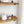 a set of wooden shelves with various items on them, including a white ceramic container, a wooden jar, and a white bowl. The shelves are set against a white brick wall, creating a clean and minimalist aesthetic.