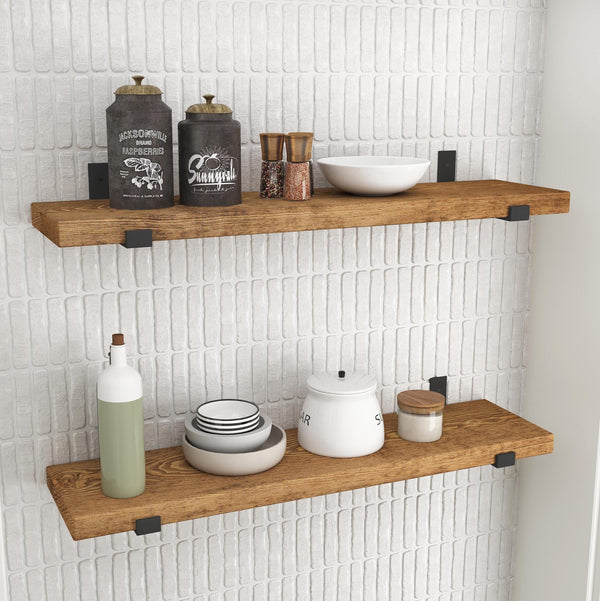 a set of wooden shelves mounted on a white tiled wall, displaying various kitchen items such as bottles, bowls, and a candle.