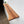 a wooden shelf mounted on a white wall, with a small potted plant placed on top of it.