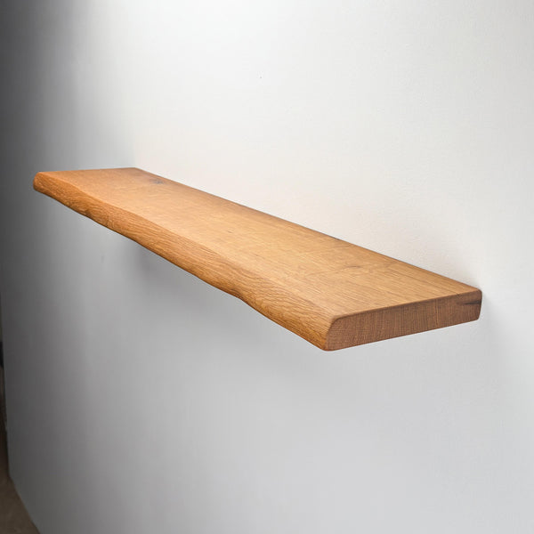 A simple, wooden shelf mounted on a white wall.