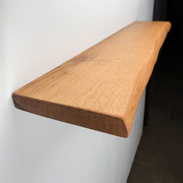 A wooden shelf mounted on a wall, with a natural, light-colored finish.