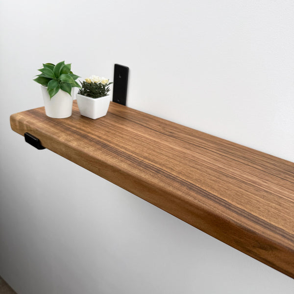 a wooden shelf with two potted plants placed on it.
