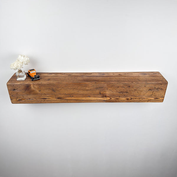 a wooden shelf mounted on a wall, with a vase of white flowers and a small toy truck placed on it.