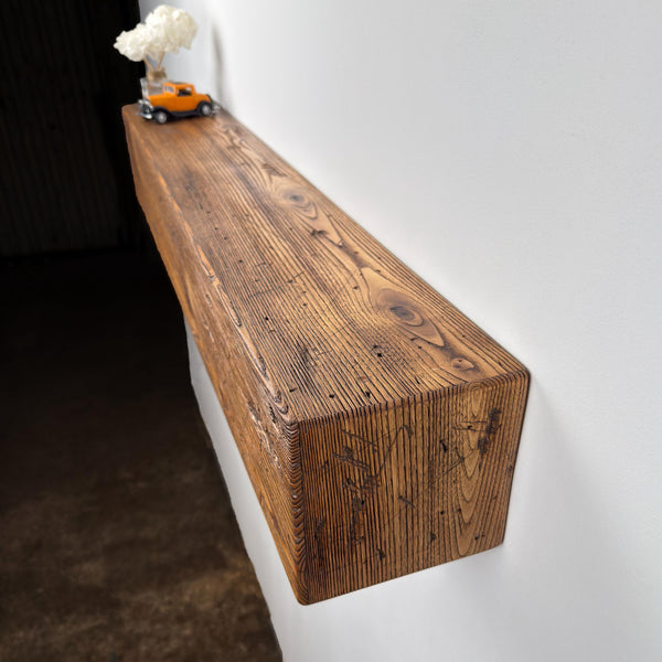 a wooden shelf mounted on a wall, with a small orange toy truck placed on top of it.