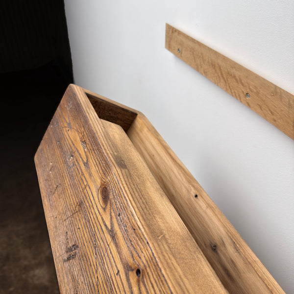 a wooden shelf mounted on a wall, with a dark background.