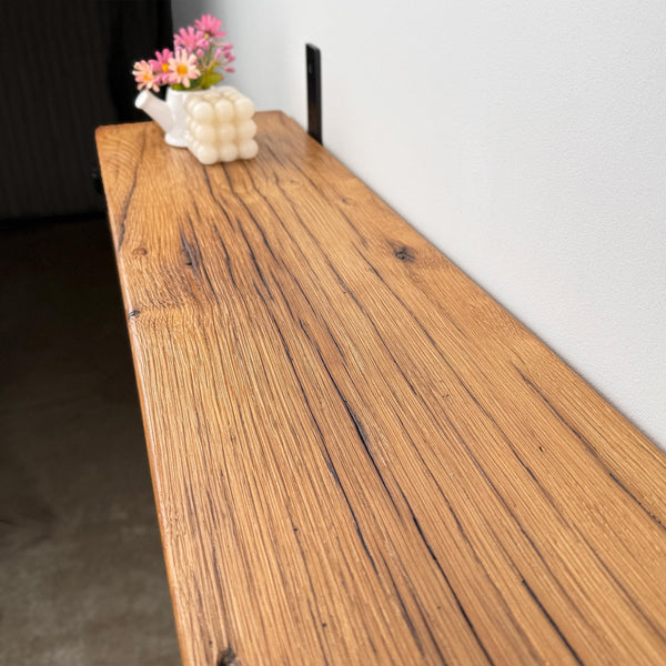 a wooden shelf or table with a vase of flowers and a white cube-shaped object on top.