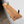 a wooden shelf mounted on a wall, with a small vase of flowers on top of it.
