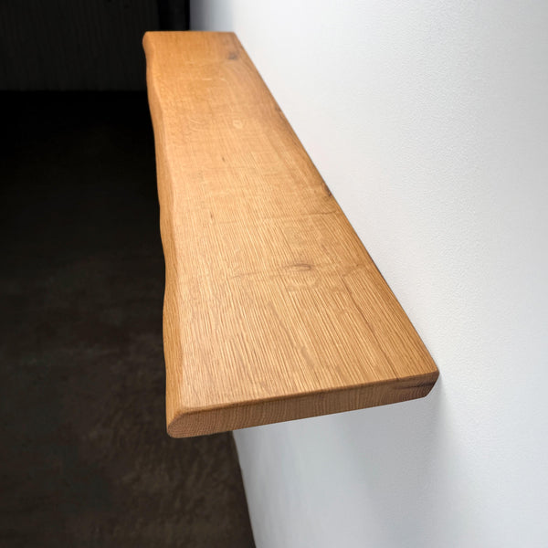 A wooden shelf mounted on a white wall, with a dark background.