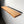A wooden shelf mounted on a white wall, with a black metal bracket supporting it.