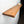 A wooden shelf mounted on a white wall, with a small plant on the shelf and a white object on the wall.