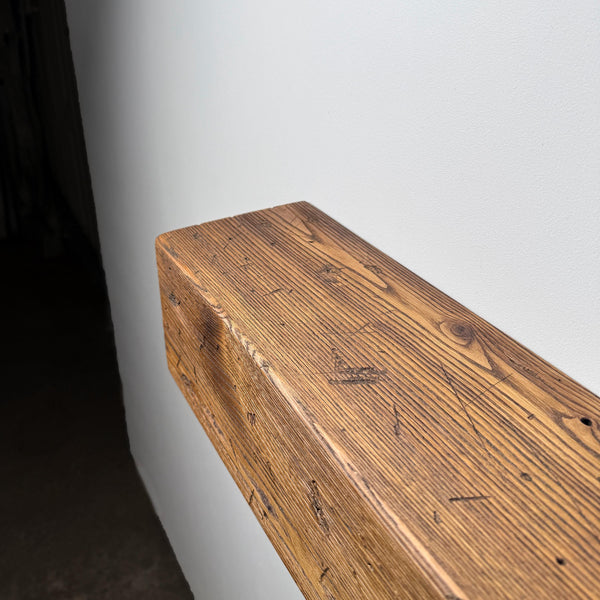 a wooden shelf or mantle against a white wall.