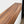 a wooden shelf or ledge with a natural wood grain texture, mounted on a white wall.