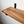 a wooden shelf mounted on a wall, with a black metal bracket attached to the wall.