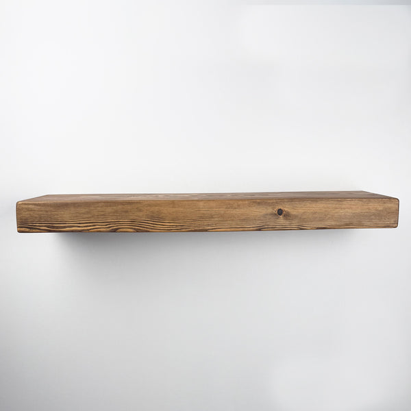 A simple, wooden floating shelf against a white wall.