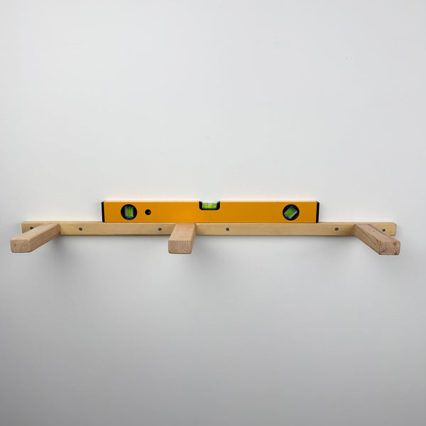 a yellow level with a wooden shelf attached to a white wall.